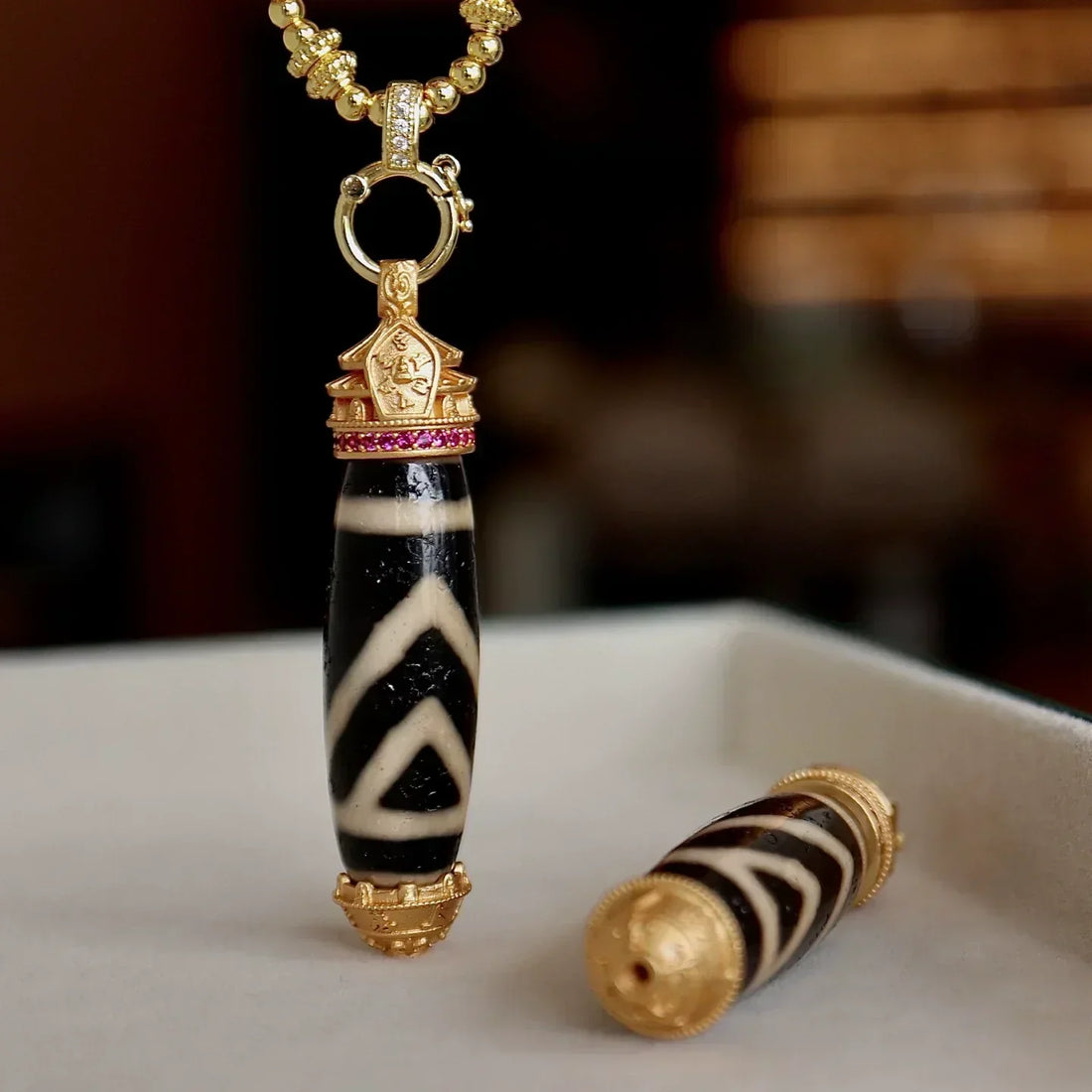 one eye Dzi bead pendant with gold details, symbolizing protection and stability