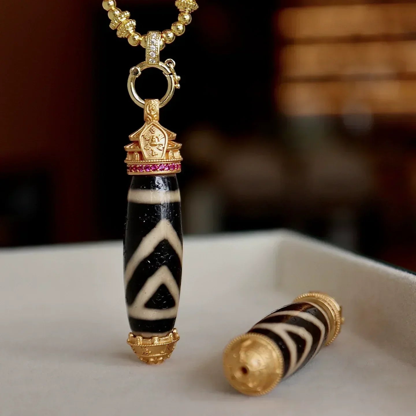 one eye Dzi bead pendant with gold details, symbolizing protection and stability