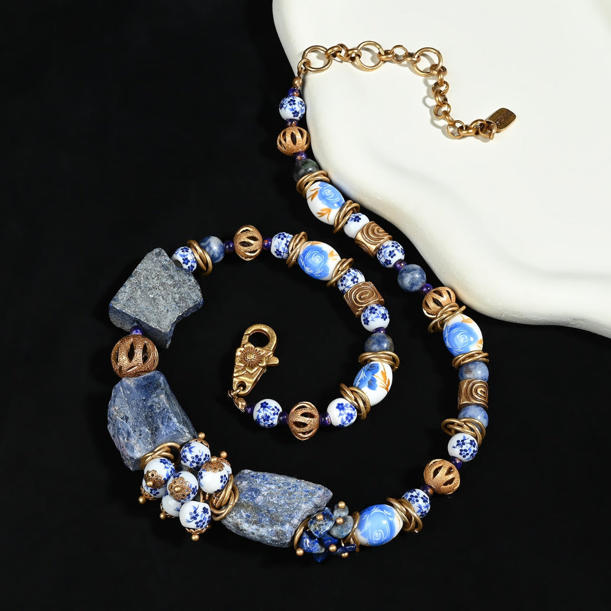 Handcrafted lapis lazuli and porcelain necklace displayed on natural stone surface